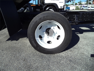 Isuzu NRR dump truck wheel/view showing front tire and white steel rim with bolts, undercarriage and frame in background.