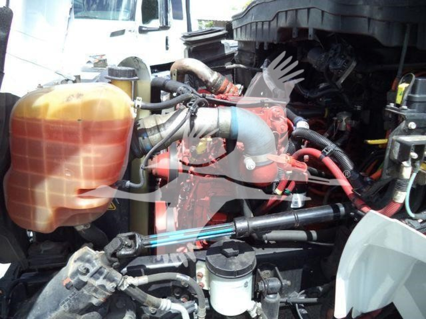 Engine bay of a 2019 International 4300 dump truck showing coolant reservoir, hoses, and hydraulic lines