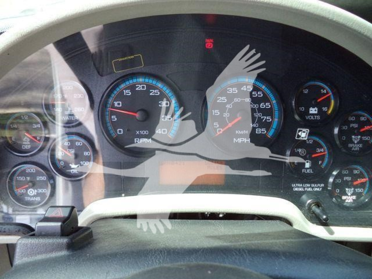 Dashboard gauges of a 2019 International 4300 truck showing multiple analog dials including tachometer, speedometer, fuel, and other warning lights. The overlay watermark includes a hand graphic.