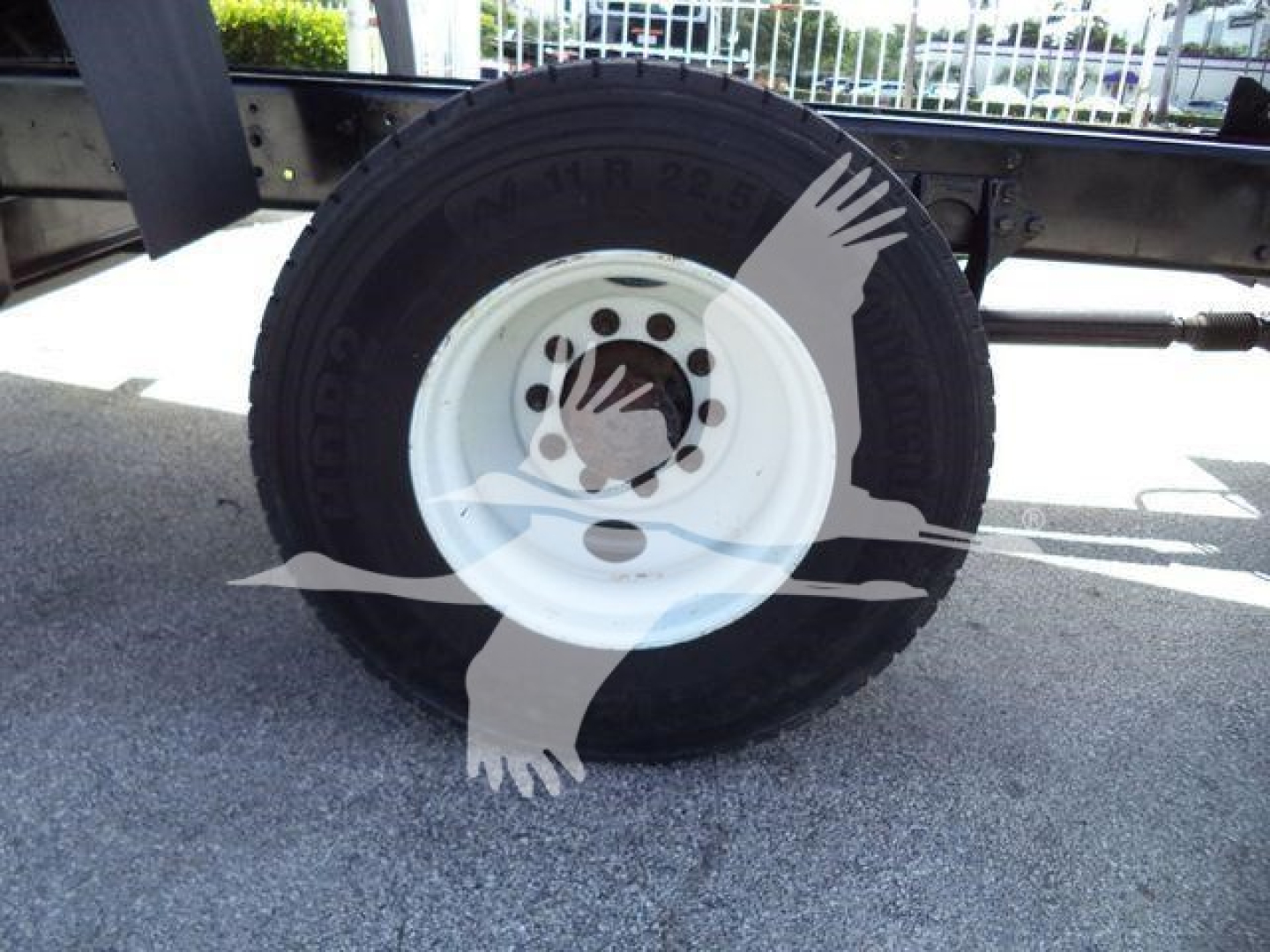 Wheel showing a white steel rim and tire on a dump truck. Visible text on tire reads MN 22.5 M? and wheel hub with bolt holes.