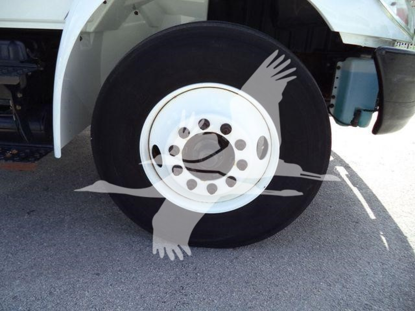 Truck wheel and front fender area with a white rim and black tire, part of International 4300 dump truck.