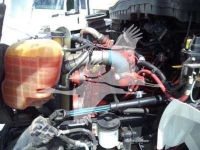 Engine bay of a 2019 International 4300 dump truck showing coolant reservoir, hoses, and hydraulic lines