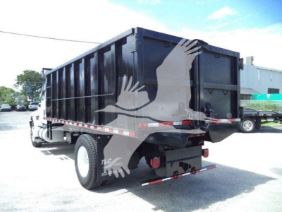 Dump truck rear and side view with black dump body, white cab, and reflective red/white stripes. Visible text includes none explicit; truck silhouette and rear bumper.