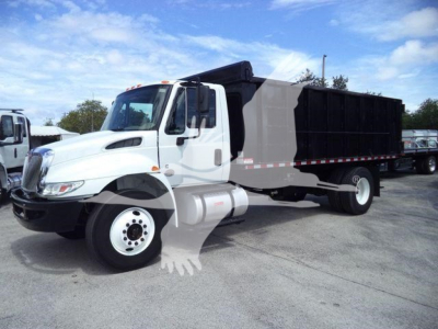 International dump truck with white cab and black dump body, side view in lot.