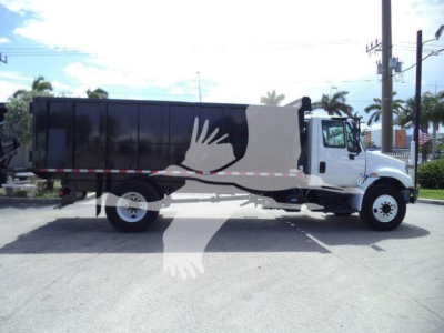 Truck side view showing a black dump bed on a white International 4300 with logo/graphic depicting a white hand and blue background.