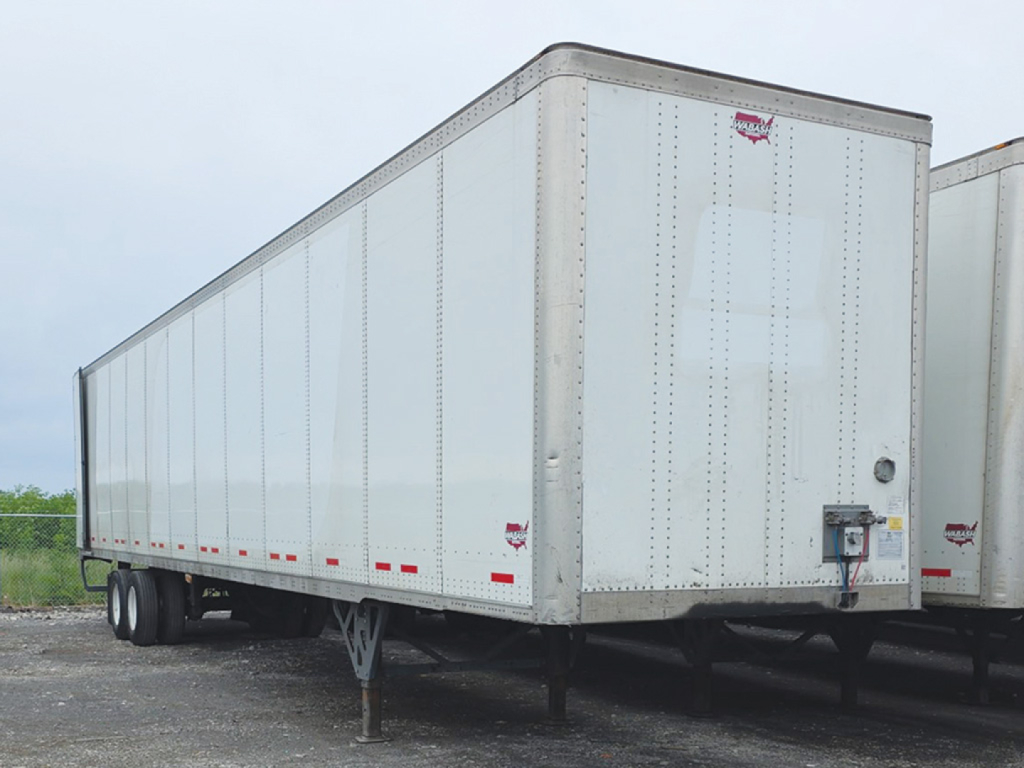 Trailer side and rear view of a white 2023 Wabash DuraPlate van trailer showing aluminum panel exterior and hitch area.