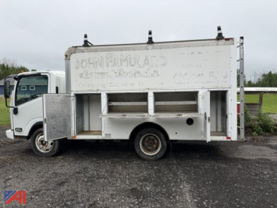 Isuzu NPR box truck side view with service opening doors and white box body. Faded lettering on side reads JOHN FAMULARD? and other indistinct words. Side compartments and a single rear wheel visible.
