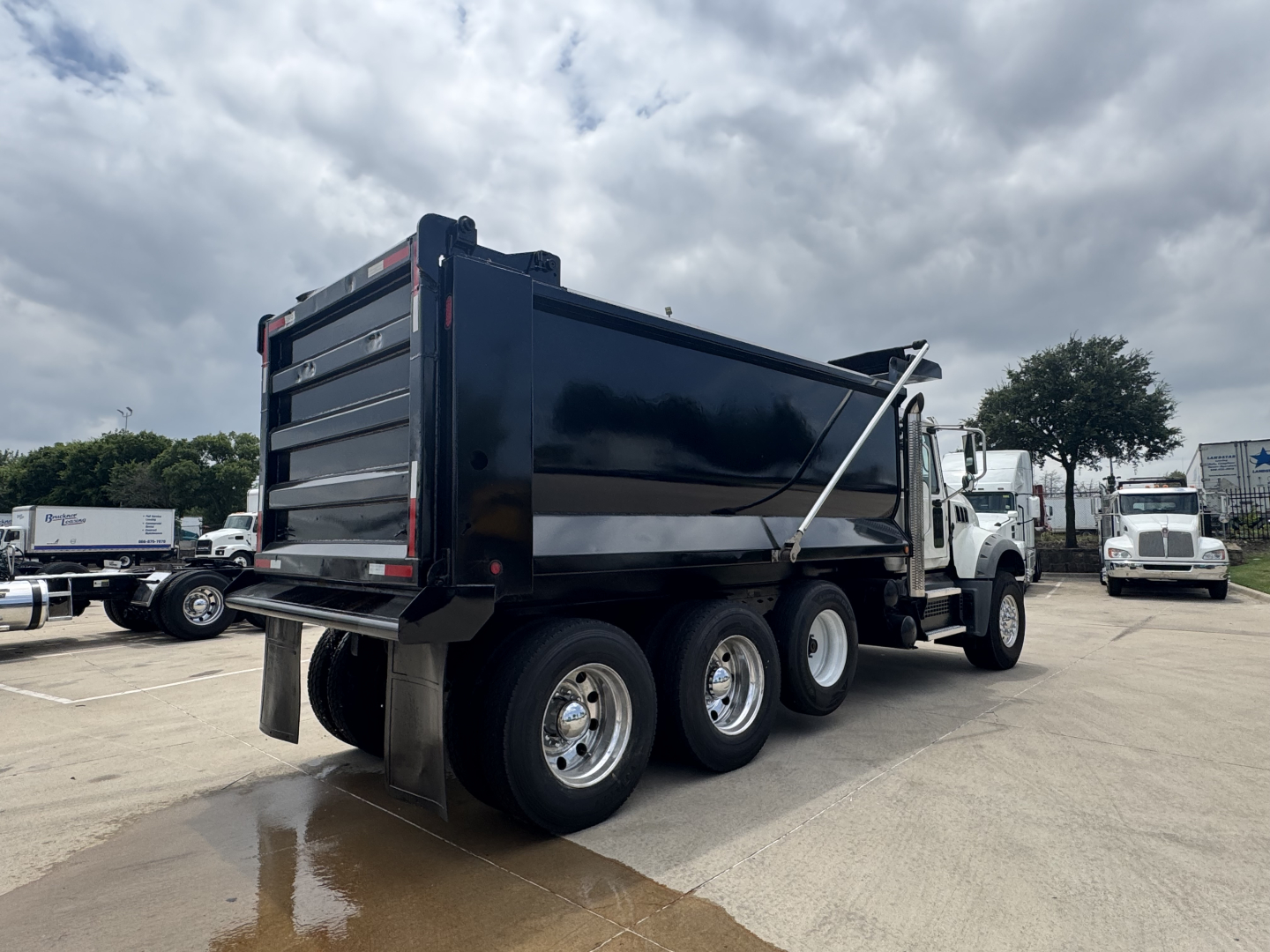 2021 Mack GR64F dump truck rear three-quarter view showing dump bed and dual rear axles with mud flaps.