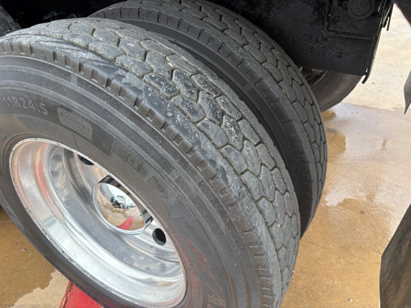 Wheel and dual tires of a Mack GR64F truck showing tire sidewall markings and chrome wheel.