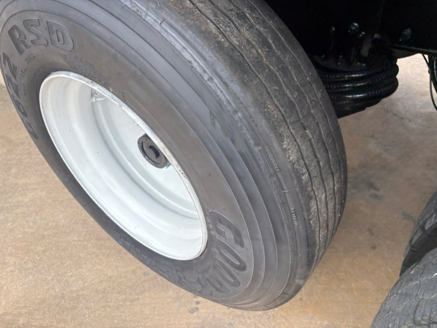 Mack GR64F wheel tire close-up showing Goodyear RSD dual tread with white rim and hub area visible under the chassis.