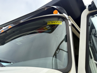 Windshield with yellow B3433F sticker on Mack GR64F dump truck cab window