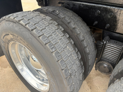 Dual rear axles and heavy-duty tire on Mack GR64F truck showing dual rear wheels and differential housing with suspension leaf spring.