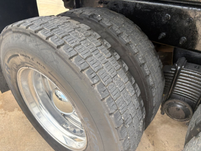 Rear dual tires on a Mack GR64F dump truck showing tread, wheel, and suspension components.