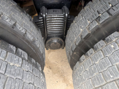 Mack GR64F truck dual rear dual tires view showing driveline and differential housing between wheels.