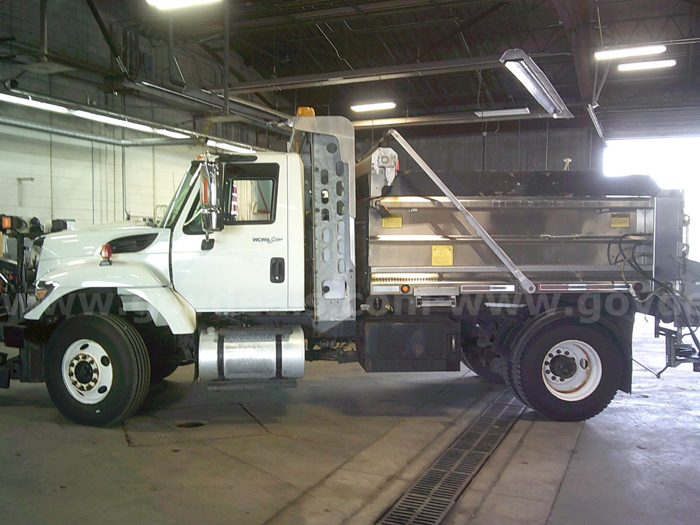 2011 International WorkStar 7400 dump truck side view showing cab, chassis, and dump body inside garage.