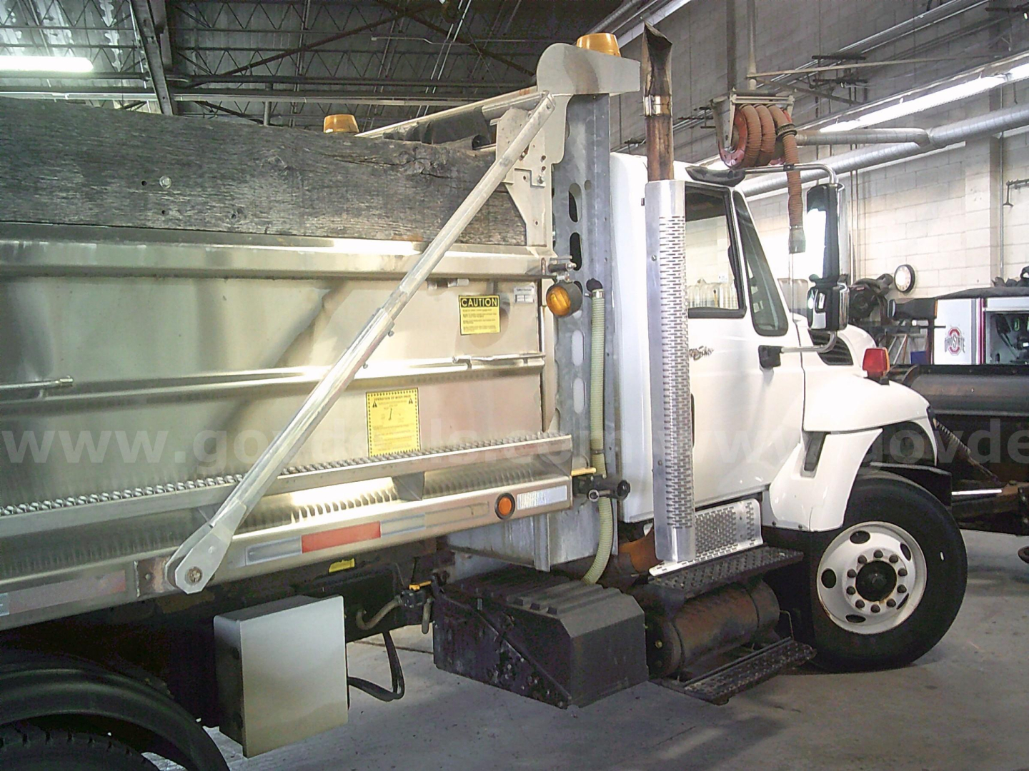International WorkStar 7400 dump truck side view showing dump bed, hydraulic hoist, and cab with steps.
