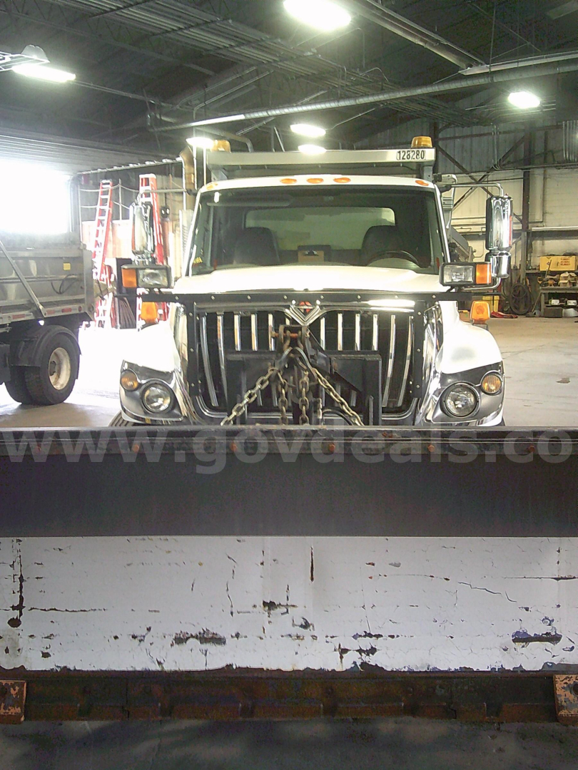Dump truck front view showing International WorkStar 7400 with chained grille, headlamps, and large bumper in an indoor lot.