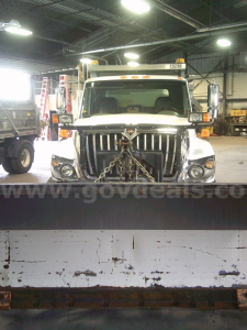 Dump truck front view showing International WorkStar 7400 with chained grille, headlamps, and large bumper in an indoor lot.