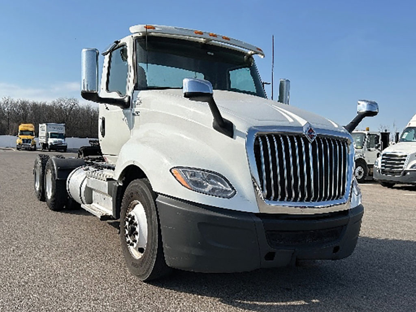 Truck side view showing 2019 International LT625 conventional daycab, front grille, dual rear axles, white cab, black bumper, on lot.