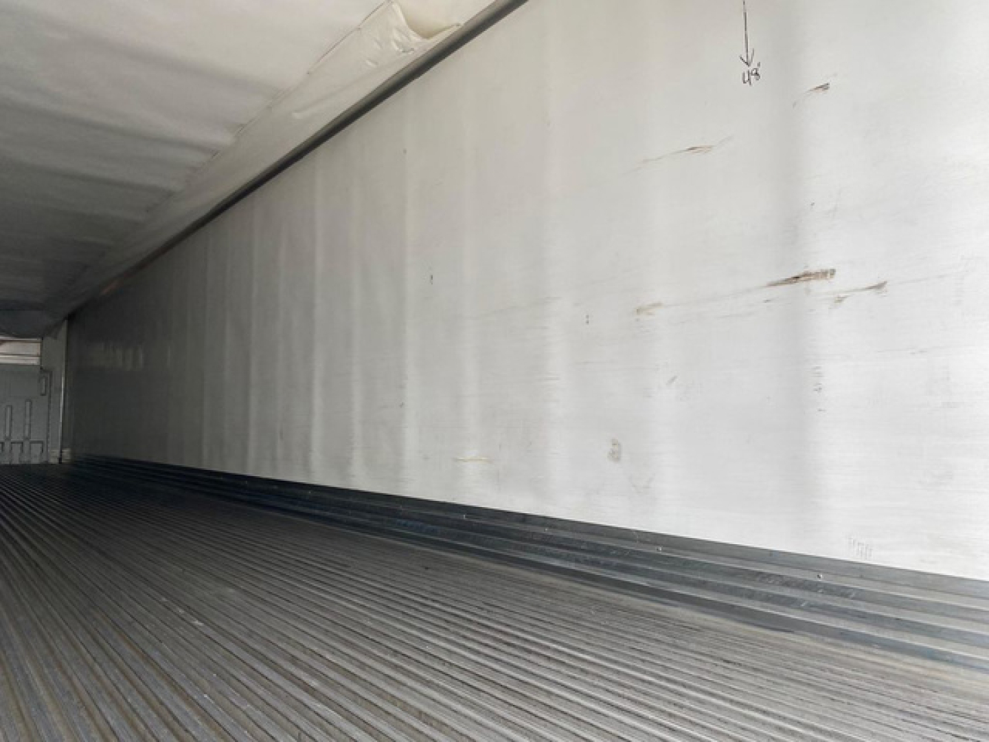 Trailer interior showing empty refrigerated trailer with ribbed floor and smooth white side walls.