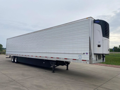 Trailer side view showing a refrigerated box truck trailer with a reefer unit at the front. Silver corrugated metal exterior, two axles, landing gear, and rear doors not visible.