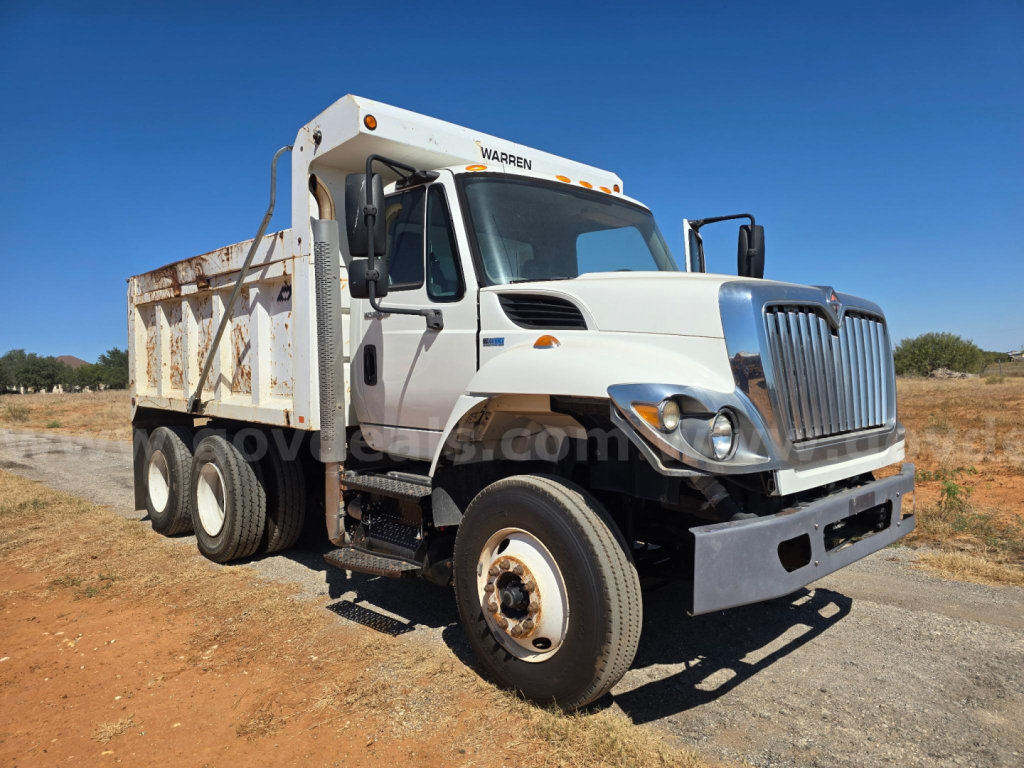 Dump truck 2013 International 7400 with white cab and dump body, stock number 23845-109, front view in dirt lot.