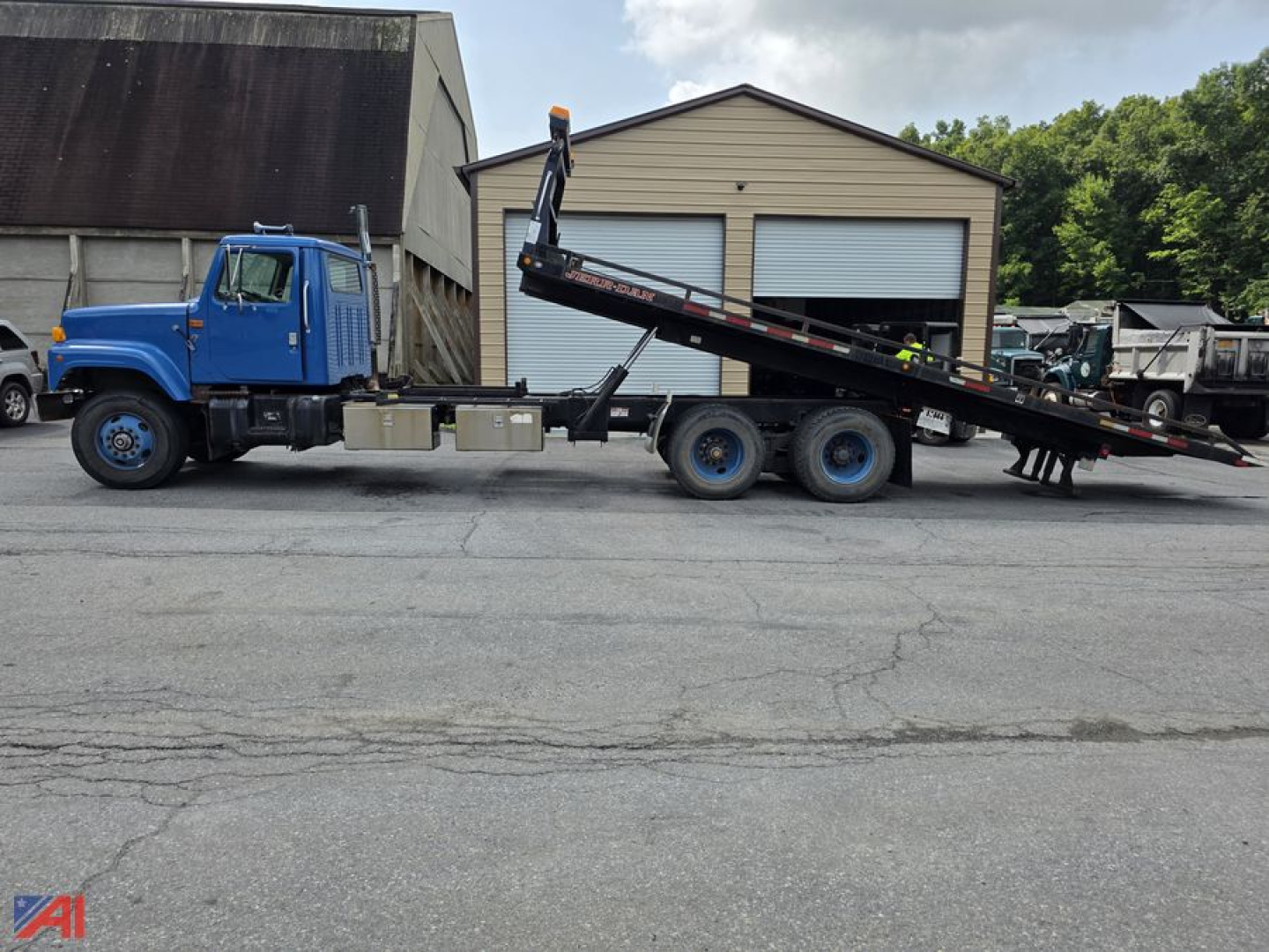 2000 International 2574 rollback tow truck side view showing long hydraulic bed and wheel assembly