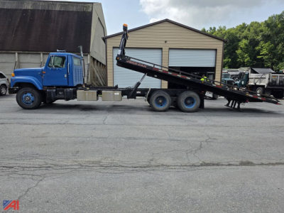 2000 International 2574 rollback tow truck side view showing long hydraulic bed and wheel assembly