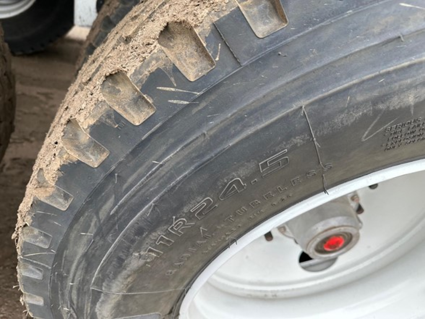 Tire close-up on a bottom dump trailer showing large off-road tread and wheel assembly.
