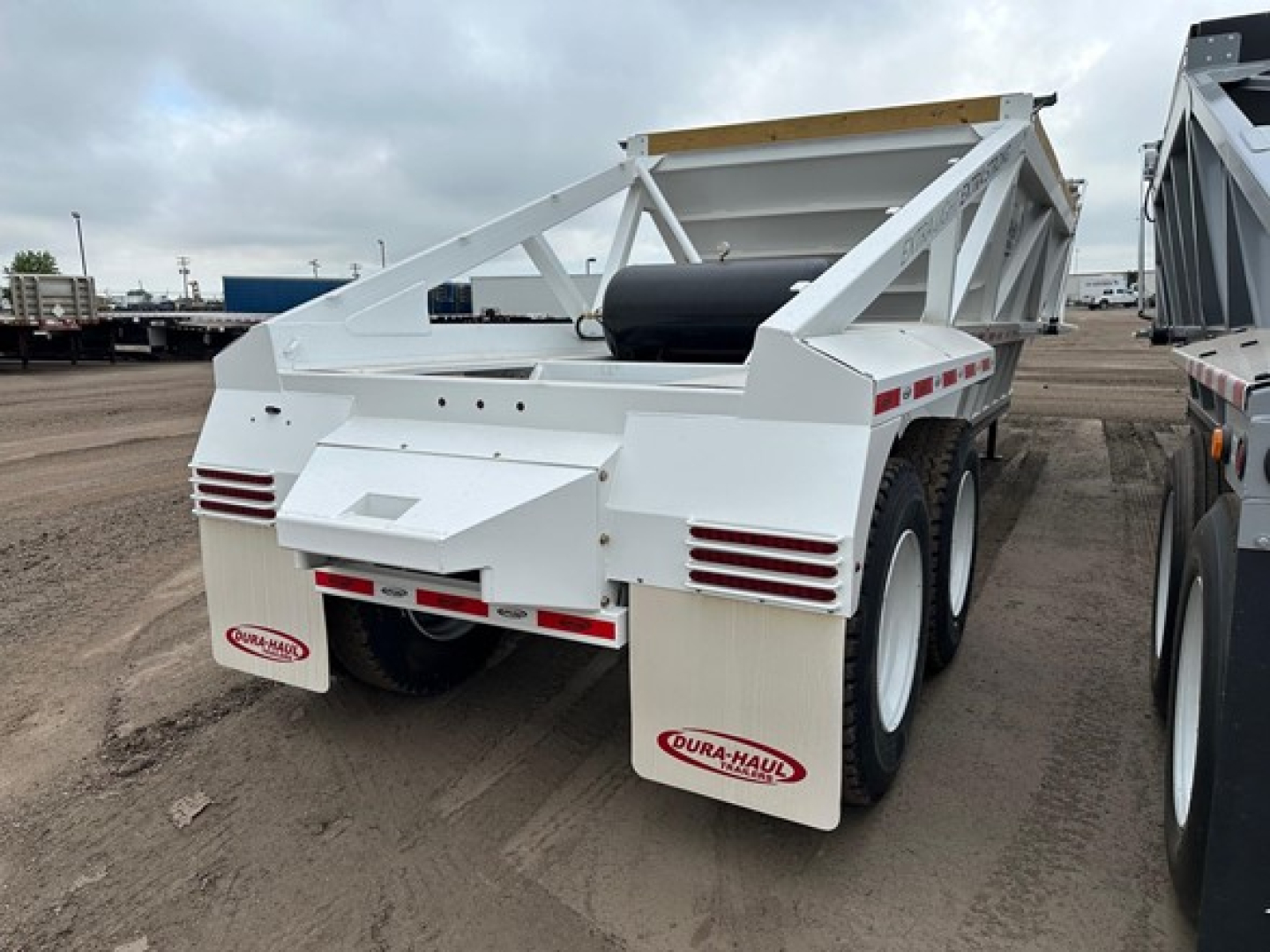 Trailer rear view of a white 2026 Dura Haul light weight bottom dump with dual rear mud flaps showing logos and taillights.