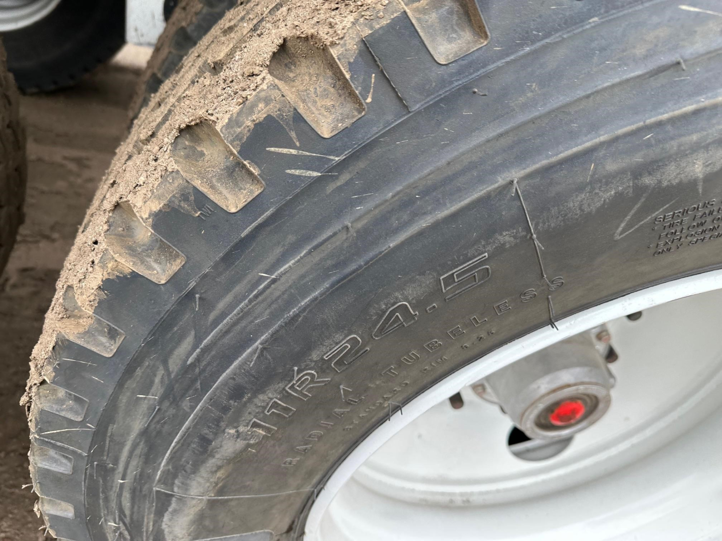 Tire and wheel of a bottom dump trailer showing rugged tread and rim.