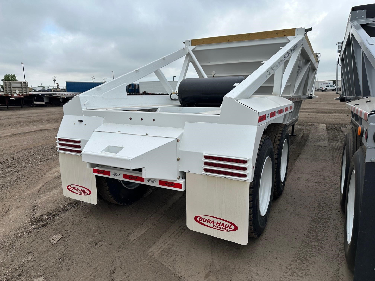 Trailer rear view showing white Dura Haul light weight bottom dump with dual axles and mud flaps, stock NE11446 visible.