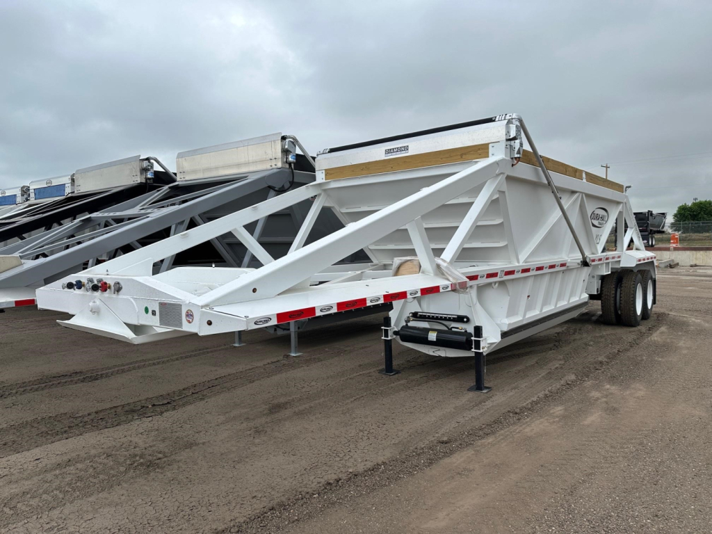 Trailer side view of a white Dura Haul light weight bottom dump trailer showing alloy frame, dual rear axles, and rear support legs.