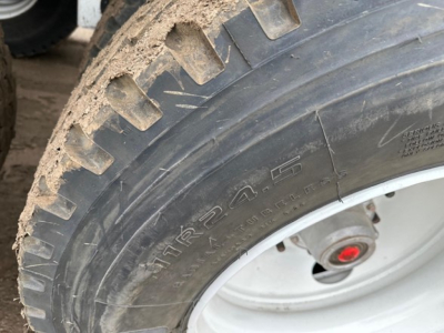 Tire close-up on a bottom dump trailer showing large off-road tread and wheel assembly.