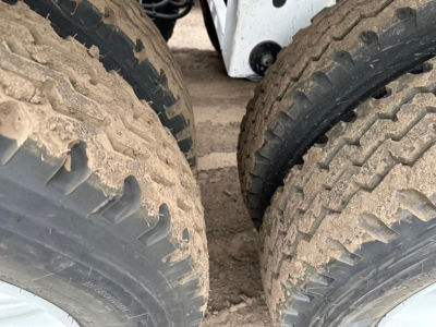 Bottom dump trailer tires and undercarriage visible, heavy tread, dirt on tires.