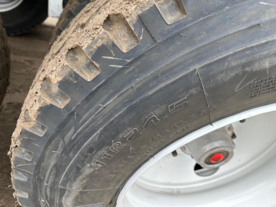 Tire and wheel of a bottom dump trailer showing rugged tread and rim.