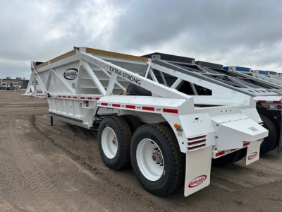 Trailer side view showing Dura Haul light weight bottom dump with white frame and dual axles; says EXTRA-STRONG on beam and has branded mud flaps.