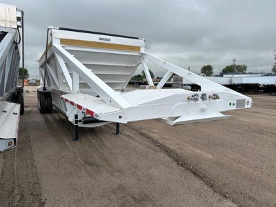 Bottom dump trailer in white with triangular lattice frame and hopper, side rails, and front hitch area visible.