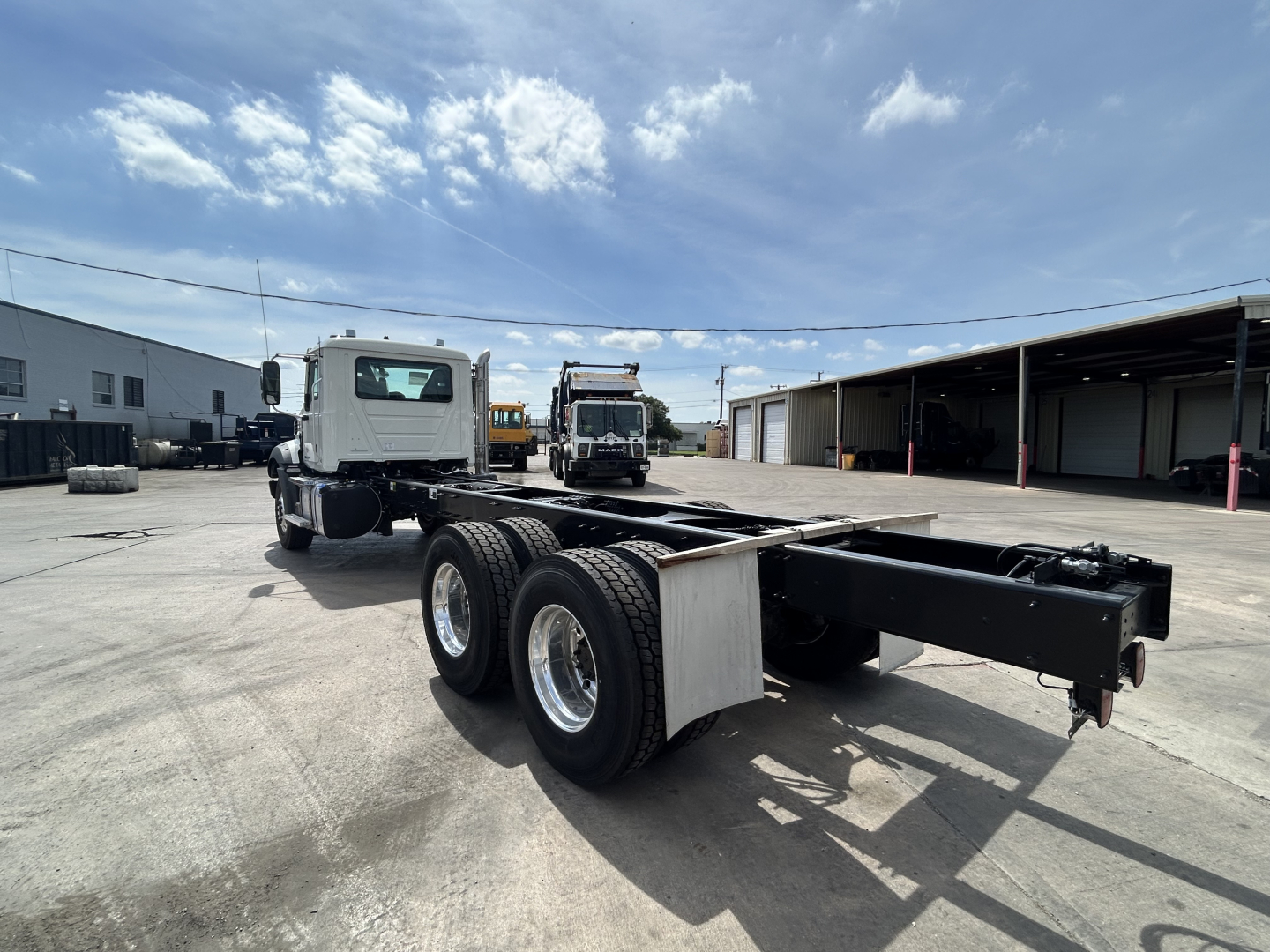 Mack GR64B chassis showing long wheelbase with dual rear axles and empty truck bed area, view from left rear side.