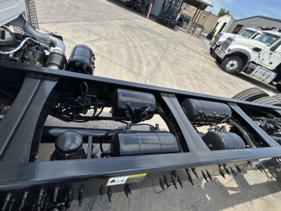 Truck chassis frame rails and underbody components of a 2026 Mack GR64B rolloff showing fuel tanks and hydraulic lines.