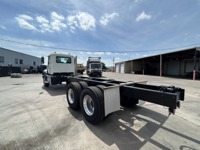 Mack GR64B chassis showing long wheelbase with dual rear axles and empty truck bed area, view from left rear side.