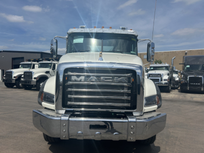 Front view of a white 2026 Mack GR64B roll-off truck showing large chrome grille, Mack emblem, dual side mirrors, and chrome bumper.
