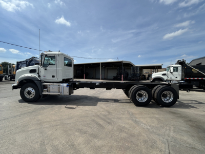 Mack GR64B roll-off truck side view showing cab with long wheelbase and empty flatbed frame, 6x4 configuration with dual rear axles.