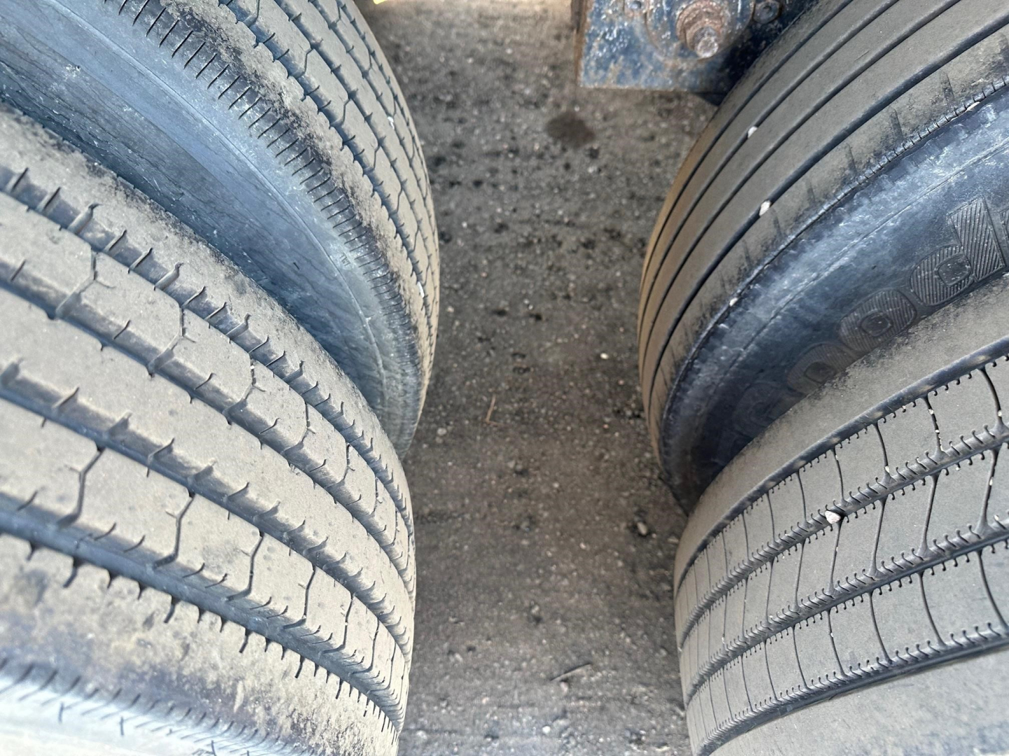 Twin tires of a forklift kit trailer with visible tread and dirt, top view showing wheel assemblies and gap between tires.