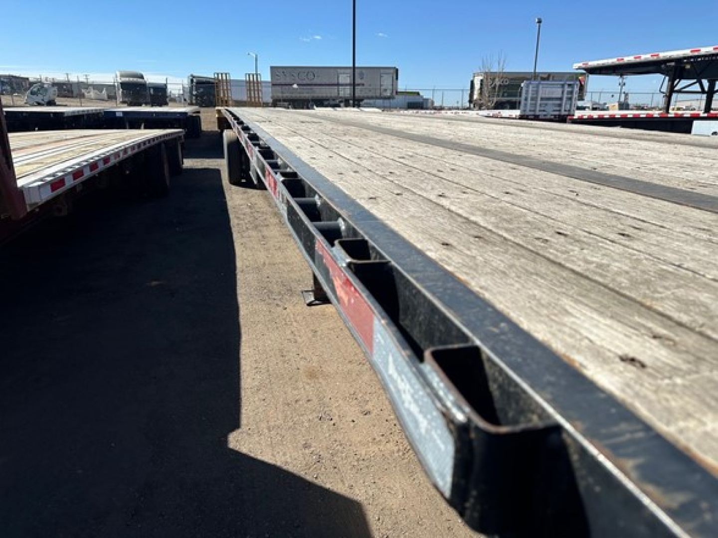 Flatbed trailer deck showing weathered wooden slats and steel side I-beams from a top-down perspective