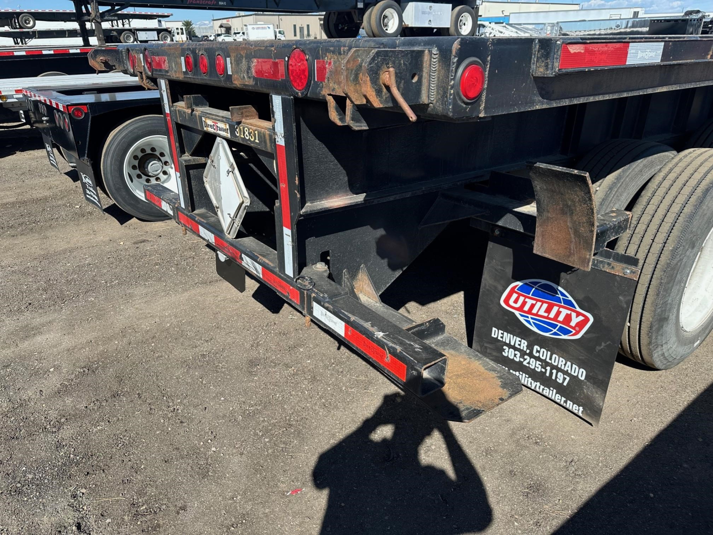 Trailer rear view showing flatbed trailer with Utility logo, rear lights, and wheel, stock number UE11423, VIN 150119763322, flatbed/ trailer components visible.
