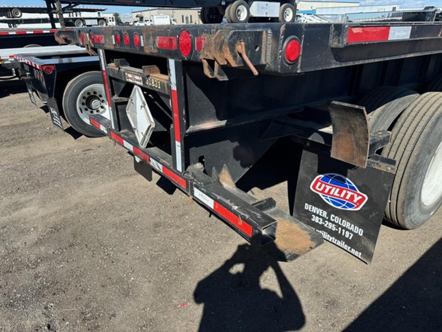 Flatbed trailer rear view with wheel, mudflap, and Utility logo; visible text includes Utility Colorado contact on mudflap and reflective tape along bed.
