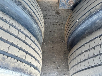 Flatbed trailer tires and undercarriage visible with dual wheel setup, showing tread and chain of wear consistent with used equipment.