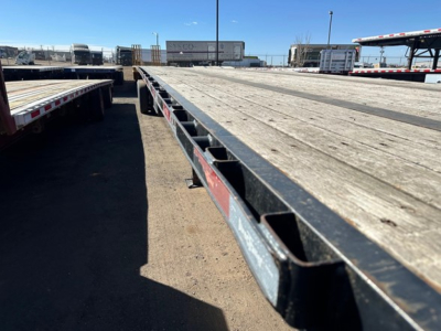 Flatbed trailer deck showing weathered wooden slats and steel side I-beams from a top-down perspective
