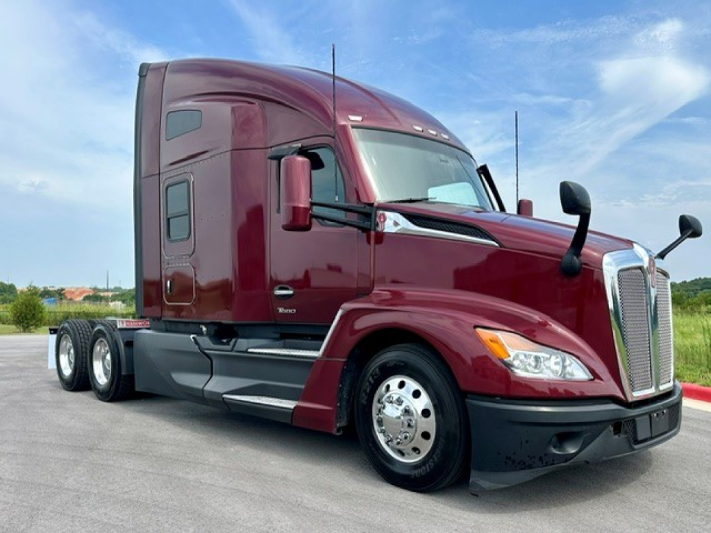 Kenworth T680 tractor-trailer cab in maroon, side view, with sleeper, front grille, dual rear axles, aluminum wheels.